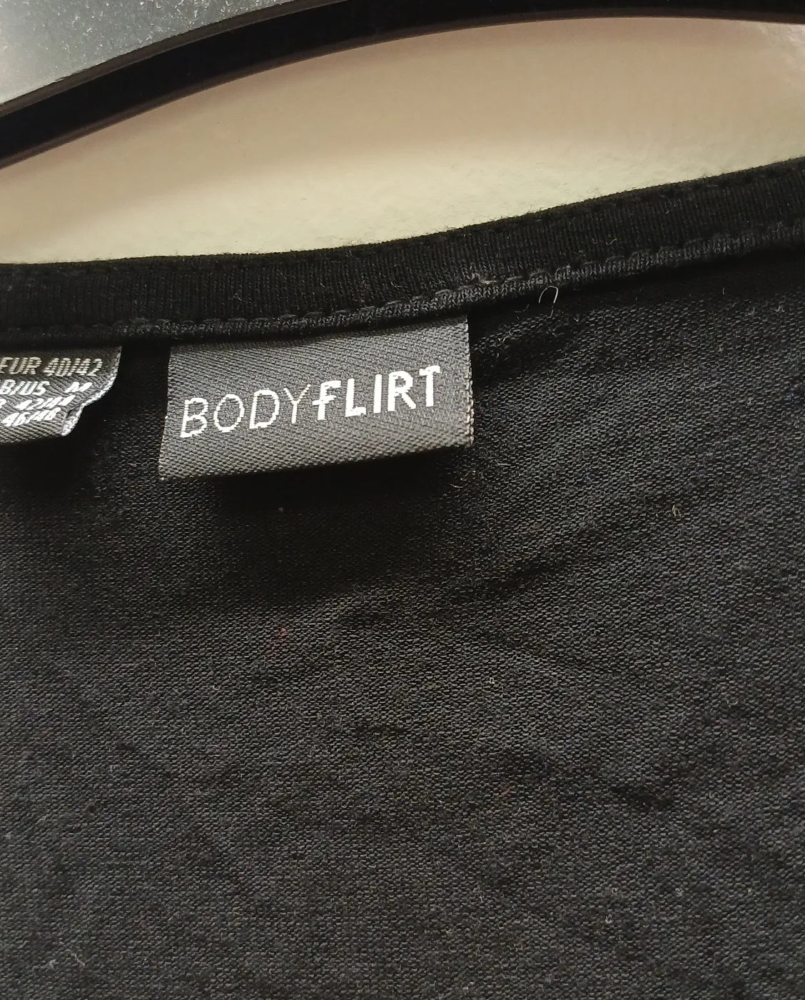 Bodyflirt svart linne med lager-på-lager fåll och dragkedja